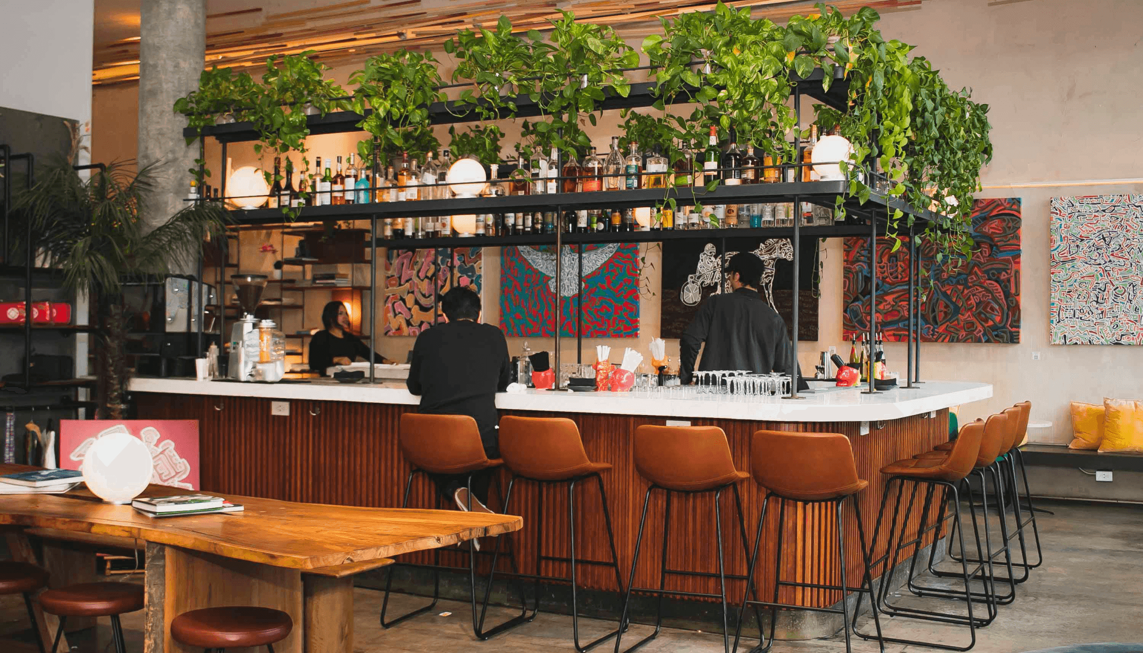 The lobby bar trailing with greenery, leather stools and artwork along the back wall