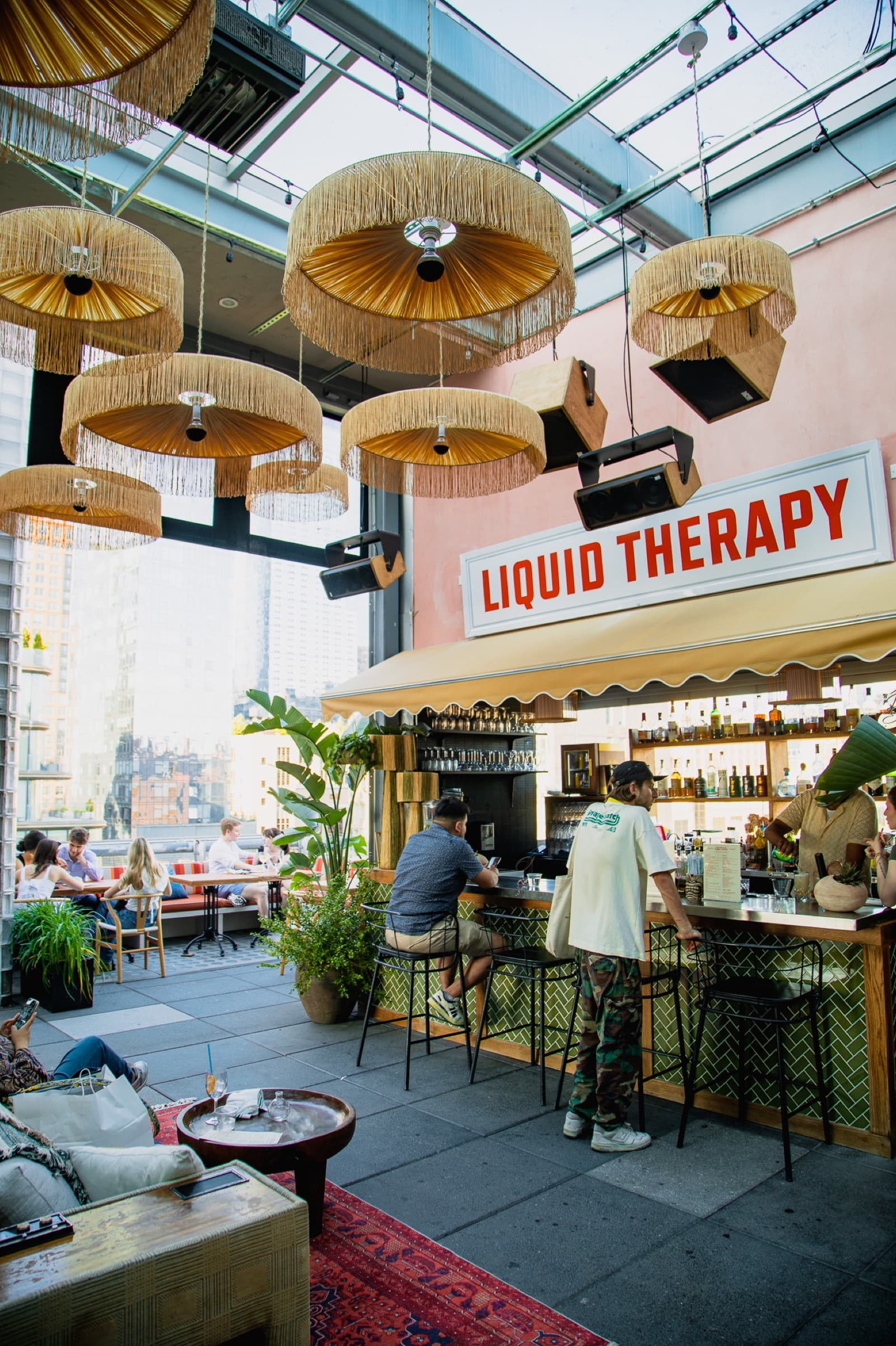 Guests at the Liquid Therapy bar on Creatures Rooftop in golden hour light